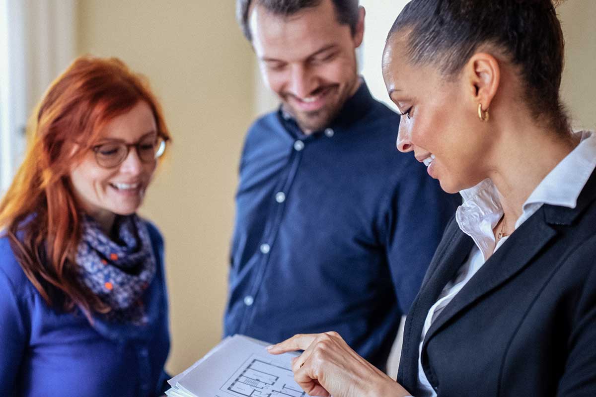 Kolme henkilöä tarkastelee yhdessä kodin pohjapiirrosta.