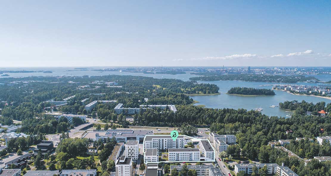 Ilmakuva Helsingin Laajasalosta, jossa näkyy merellistä maisemaa, vehreitä metsäalueita ja modernia asuinrakentamista. Kuvassa on merkitty Laajasalon Kaiku -niminen kortteli