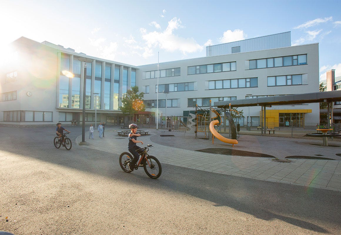 Lapsia py&ouml;r&auml;ilee Vattuniemen ala-asteen koulun ja p&auml;iv&auml;koti Meren pihalla. Taustalla on kiipeilyteline ja liukum&auml;ki.