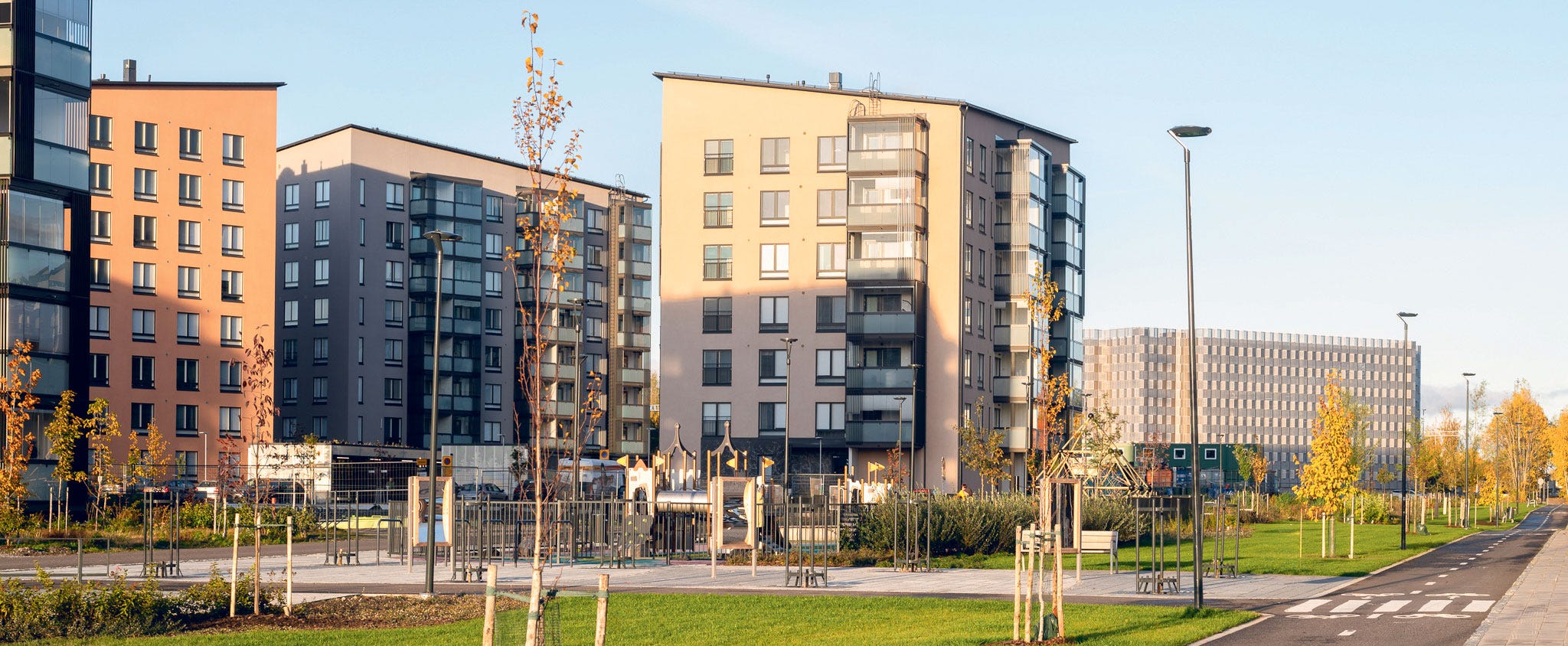 Kirstinpuiston asuinalue aurinkoisessa säässä. Kuvassa korkeita kerrostaloja, vehreitä nurmialueita, kävely- ja pyöräteitä sekä leikkipuisto.