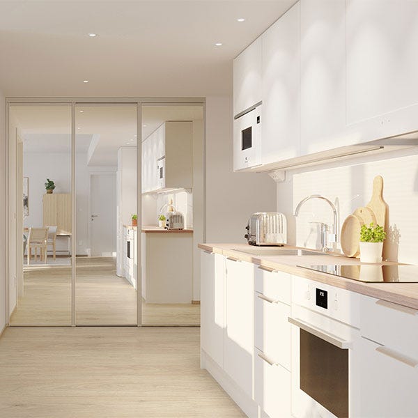 Moderni vaalea keittiö, jossa on puiset työtasot, integroidut kodinkoneet ja runsaasti luonnonvaloa.