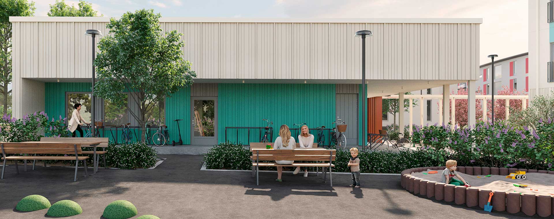Seelan yhteiskäyttöinen piharakennus, jossa turkoosi ja valkoinen ulkoseinä. Edustalla penkkejä, pyörätelineitä ja leikkivälineitä. Lapset leikkivät hiekkalaatikossa ja aikuiset keskustelevat penkillä.