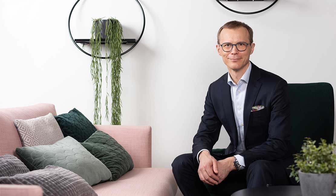 Keskinäinen luottamus on kehittymisen edellytys Bonava Suomi Oy:n toimitusjohtaja Riku Patokoski istuu modernissa ja tyylikkäästi sisustetussa tilassa vaaleanpunaisella sohvalla, jonka päällä on vihreitä ja harmaita tyynyjä. Taustalla seinälle ripustettuja viherkasveja pyöreissä hyllyissä.