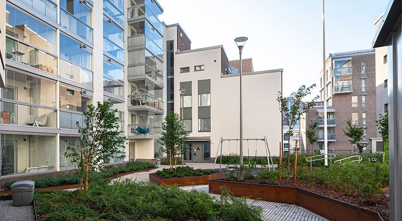 Ellen, Helsinki Modernien kerrostalojen ympäröimä vehreä sisäpiha, jossa istutuksia, kävelyreittejä ja istuinalueita.