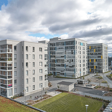 Lielahden kotikorttelin moderneja kerrostaloja Tampereella. Vaaleasävyisten talojen arkkitehtuuria korostavat lasitetut parvekkeet ja yksityiskohdat. Pihatilassa vihreä nurmialue, pyöräkatoksia ja kulkuväyliä, taustalla lisää asuintaloja.