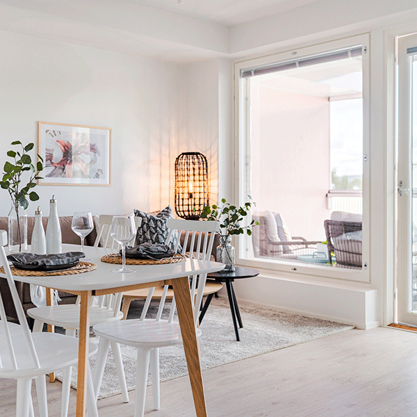 Elegantti ruokailutila, jossa skandinaavinen sisustus yhdistyy lämpimiin yksityiskohtiin. Suuri ikkuna avautuu lasitetulle parvekkeelle, ja pehmeä valaistus luo kutsuvan tunnelman illalliskattaukselle.