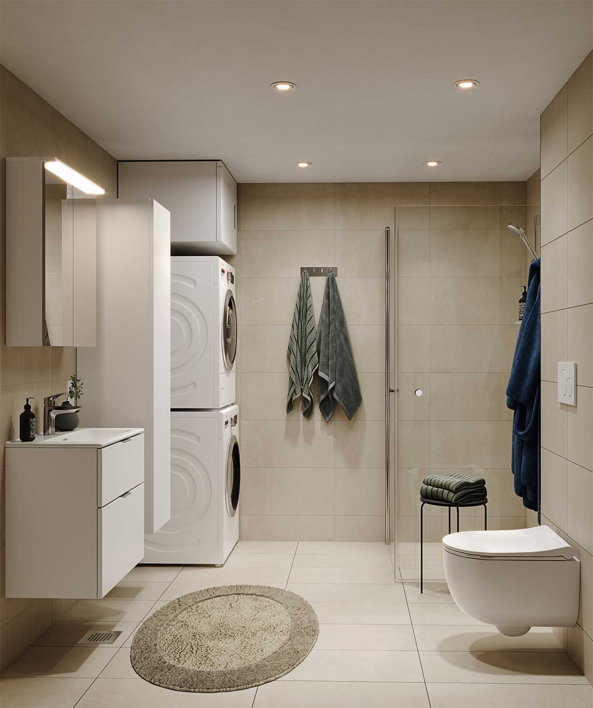 Tyylikäs kylpyhuone, jossa hiekanväriset lattia- ja seinälaatat luovat lämpimän ja harmonisen tunnelman. Valkoiset kylpyhuonekalusteet, pesutorni ja seinään kiinnitetty wc tuovat tilaan käytännöllisyyttä. Lasiseinällä rajatussa suihkutilassa on suihku. Sisustusta täydentävät pyöreä beige kylpyhuonematto, tummansiniset ja vihreät pyyhkeet sekä pieni musta jakkara, jonka päällä on siististi viikattuja pyyhkeitä.