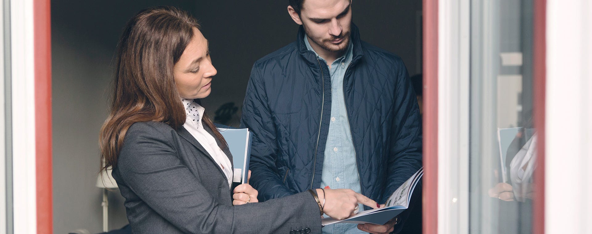 Asuntomyyjä esittelee asunnon asiakkaalle, keskustellen rauhallisesti asunnon yksityiskohdista, luoden luottamuksellisen ja turvallisen ilmapiirin kodin ostamiseen.